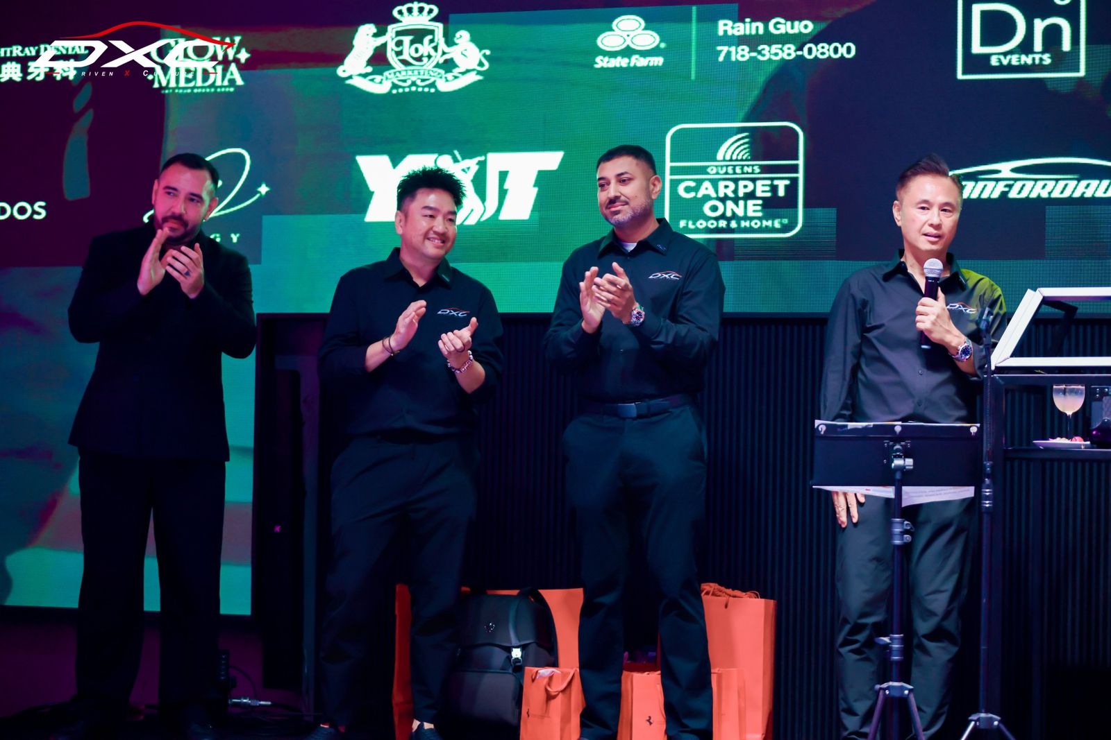 The DXC team on stage in front of the sponsor wall at DXC Launch Night