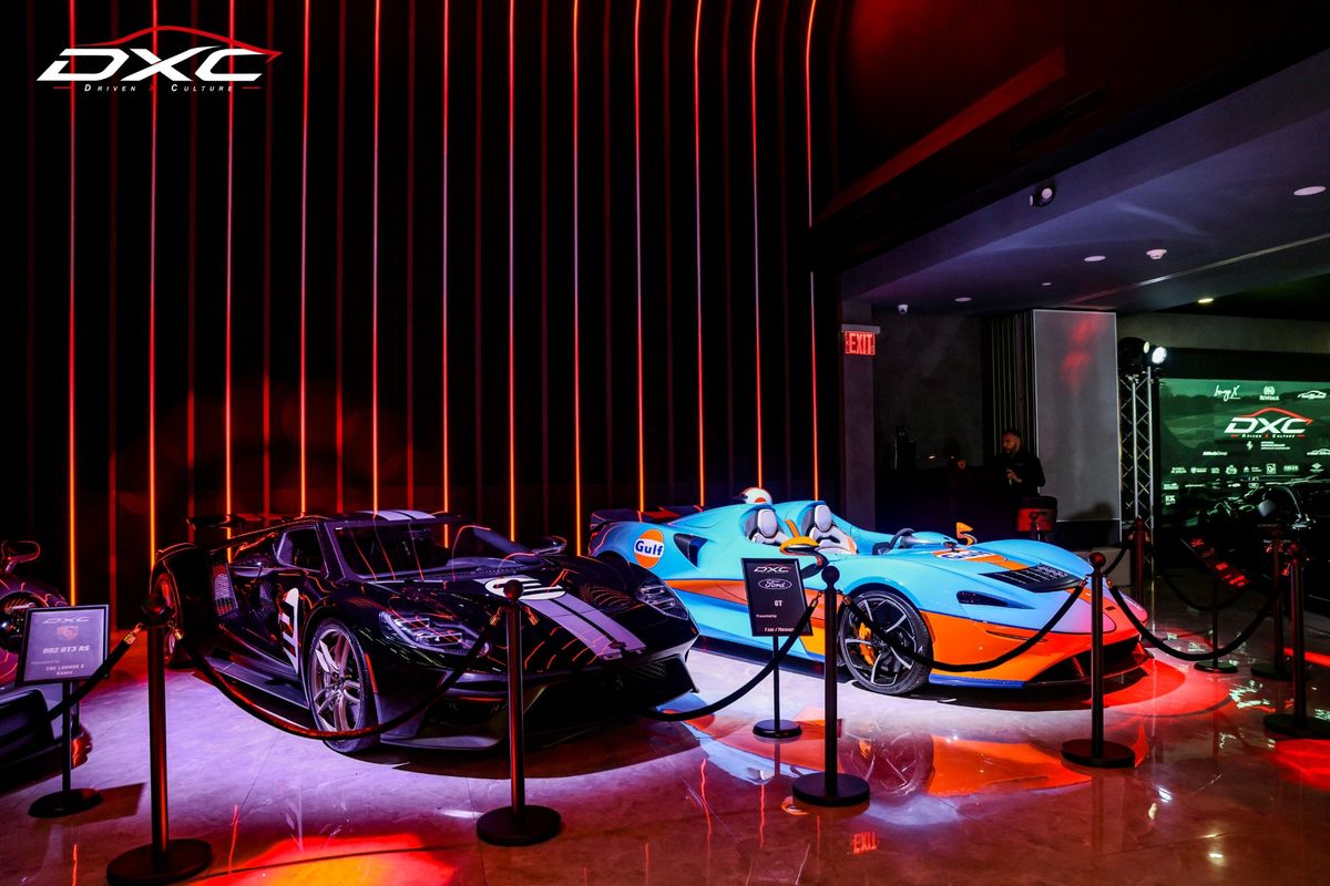 A black Ford GT and a Gulf-livery McLaren Elva roped off under red lights